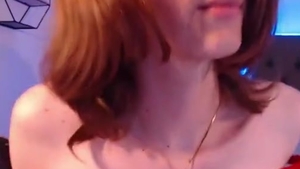 Chica trans peliroja en medias oscuras muestra su pequeño trasero